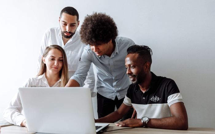 A group of colleagues discussing something on a laptop